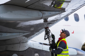 An employee of a ground service company refuels an aircraft. [Credit: Shutterstock/Karolis Kavolelis]